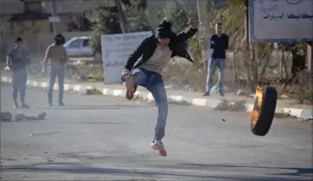  ?? MAJDI MOHAMMED, THE ASSOCIATED PRESS ?? A Palestinia­n protester kicks a tire during clashes with Israeli troops in the village of Qusra, near the West Bank city of Nablus on Thursday.