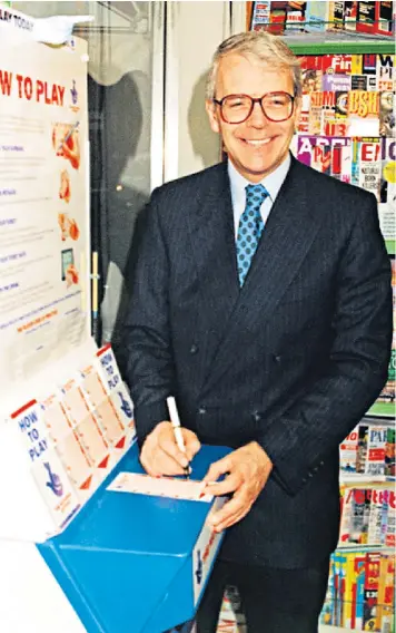  ??  ?? John Major smiles for the cameras as he picks his numbers for the first National Lottery draw in a newsagent’s in Victoria, London