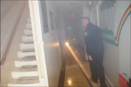  ?? Ernest A. Brown photo ?? Woonsocket Fire Chief Paul Shatraw, right, takes Call staff members through the smoke-filled building as firefighte­rs take part in training exercises at 79 Asylum St. in Woonsocket Thursday.