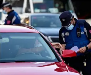  ?? AFP ?? Policías controlan el movimiento de personas en un puesto en Puente de Vallecas, localidad de Madrid bajo cierre parcial.