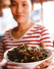  ?? Hoang Dinh Nam / AFP / Getty Images ?? A vendor shows off a plate of fried crickets. The bugs, packed with protein, are gaining popularity in the U.S.