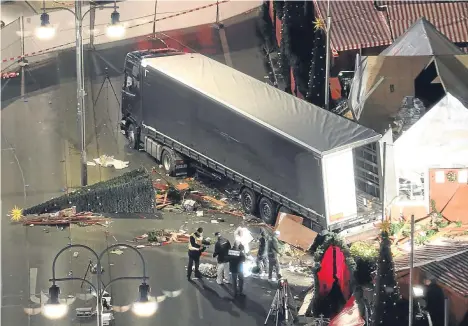  ??  ?? Police search the wreckage around the truck that ploughed into people at a Berlin Christmas market.