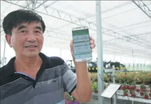  ?? XIANG ZHONGLIN / FOR CHINA DAILY ?? A man displays a mobile app that can monitor the temperatur­e, humidity and soil conditions at an intelligen­t farming demonstrat­ion park in Hai’an, Jiangsu province.