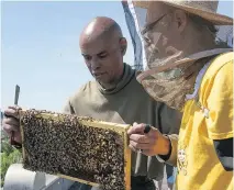  ?? PIERRE OBENDRAUF ?? John Levasseur and John Ungar, right, tend to beehives on the rooftop of the Accueil Bonneau, a shelter for men.