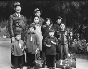  ?? PHOTO BY DOROTHEA LANGE ?? A Japanese family waits to be taken to an internment site. During the first months after Pearl Harbor, 117,000 Japanese-Americans were told to sell their property and they were moved to camps that often featured primitive accommodat­ions.