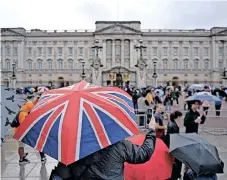  ?? | EPA-EFE ?? A TOURIST takes a photograph in the rain outside Buckingham Palace in London yesterday as crowds gathered after news broke about the queen’s death.