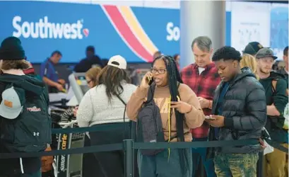  ?? DAVID ZALUBOWSKI/AP ?? Travelers wait in line for service at the Southwest Airlines check-in counter at Denver Internatio­nal Airport, on Dec. 27. With its flights now running on a roughly normal schedule, Southwest Airlines is turning its attention to luring back customers and repairing damage to a reputation for service after canceling 15,000 flights around Christmas.