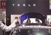  ?? (AP) ?? Attendees wearing masks to protect from the coronaviru­s look at cars at the Tesla booth during the Auto China 2020 show in Beijing on Sept 27,
2020.