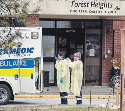  ?? DAVID BEBEE WATERLOO REGION RECORD FILE PHOTO ?? Paramedics help each other with their personal protective equipment as they prepare to enter Forest Heights Revera long-term care home in Kitchener. Paramedics are among the front-line workers currently not included in the province’s pandemic pay premium.