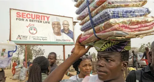  ?? AP African News Agency (ANA) ?? A STREET seller sells his wares next to a campaign poster for opposition presidenti­al candidate Atiku Abubakar at a busy intersecti­on near Nyanya, on the eastern outskirts of the capital, Abuja, on Tuesday. Nigeria is due to hold general elections tomorrow. |