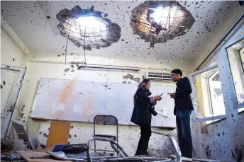  ?? — AFP photo ?? Journalist­s stand inside a damaged classroom at the National Legal Training centre a day after gunmen stormed the university in Kabul.