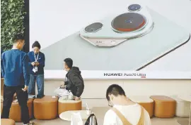  ?? REUTERSPIC ?? People sitting near a screen showing the Pura 70 as the smartphone goes on sale at Huawei’s flagship store in Beijing yesterday. –