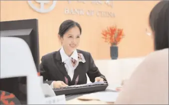  ?? -AFP ?? A Bank of China staff member serves a visitor at the China Internatio­nal Import Expo.