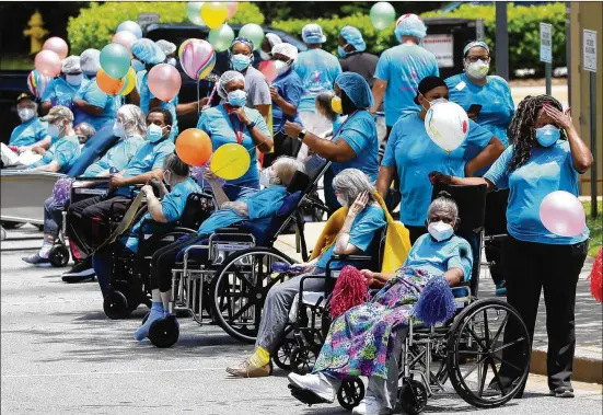  ?? PHOTOS BY CURTIS COMPTON / CCOMPTON@AJC.COM ?? Residents and staff line the curb May 13 for a community parade celebratin­g residents who survived COVID-19 at Westbury Medical Care and Rehab in Jackson. Family members and supporters decorated vehicles with signs and posters, and for many it was the first opportunit­y to see their loved ones in months.