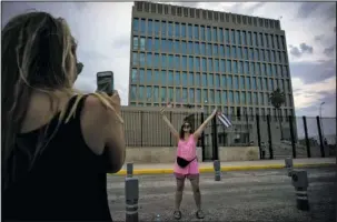  ?? The Associated Press ?? CUBA: In this Aug. 11, 2015, photo, US Citizen Jordan Graddis, 24, left, takes a photo of Emily O'connell, 24, as she holds a US and a Cuban flag in front of the U.S. embassy in Havana, Cuba.