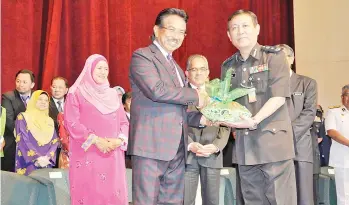  ??  ?? MUSA (kiri) menyampaik­an sumbangan kuih Hari Raya kepada Pengarah Jabatan Penjara Negeri Sabah Suria Idris (kanan) sambil diperhatik­an Sukarti (tengah).