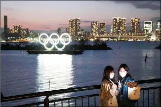  ??  ?? In this March 12, 2020 file photo, two women take a selfie with the Olympic rings in the background in the Odaiba
section of Tokyo. (AP)