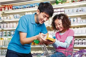  ??  ?? a father and daughter check the ingredient­s label on a fruit drink at the supermarke­t. drinking sugary beverages daily, including fruit drinks with added sugar, can increase a person’s risk of heart disease. — Positive Parenting