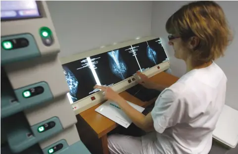  ?? (Reuters/Jean-Paul Pelissier) ?? A RADIOLOGIS­T examines breast X-rays after a cancer prevention medical check-up. Job loss rates following breast cancer diagnosis were similar for rural and urban women.