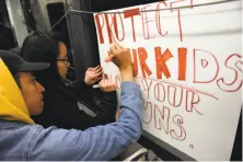  ??  ?? Lincoln High School students Marcos Ruiz and Jocelyn Chen make a sign while riding Muni to San Francisco City Hall.