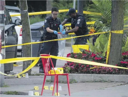  ?? TYLER ANDERSON / NATIONAL POST ?? Police officers bag evidence at the scene where a gunman shot more than a dozen people on Danforth Avenue in Toronto on Sunday night. The assault was carried out “like a Call of Duty kind of thing,” one witness said.