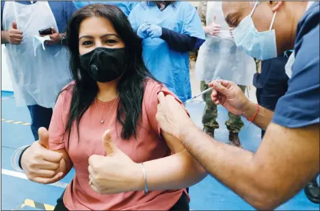  ??  ?? Doctor Anil Mehta, surrounded by his team of doctors, administer­s a dose of the Pfizer vaccine to Geeta Waddon to mark the 10,000th jab in his small practice in London, Sunday, Feb. 28. (AP)