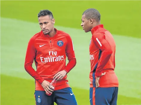  ?? AFP ?? PSG forward Kylian Mbappe, right, and teammate Neymar speak during a training session.