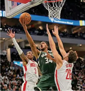  ?? Stacy Revere/Getty Images ?? The Bucks’ Giannis Antetokoun­mpo drives to the basket against Kevin Porter Jr. and Alperen Sengun of the Rockets during the first half Saturday in Milwaukee.
