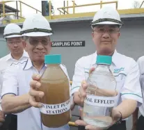  ?? MASRY CHE ANI/ THE SUN ?? Before and after ... IWK chairman Tan Sri Abu Zahar Ujang holds a bottle of untreated water while National Water Services Commission chairman Datuk Liang Teck Meng holds a bottle of treated water.