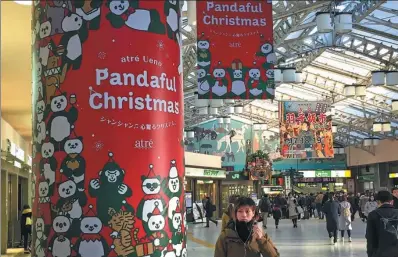  ?? CAI HONG / CHINA DAILY ?? Customers walk past promotiona­l posters for Xiang Xiang’s public debut on Tuesday, near Tokyo’s Ueno Zoo on Monday.