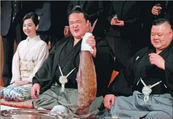  ?? TORU HANAI / REUTERS ?? Japanese sumo wrestler Kisenosato holds a red sea bream next to his stablemast­er Tagonoura and Tagonoura's wife Kotomi as he celebrates his promotion to yokozuna, or grand champion, during a ceremony in Tokyo on Wednesday.