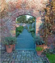  ??  ?? A view through the entrance into the walled garden, where a path is lined with luxuriant grasses.