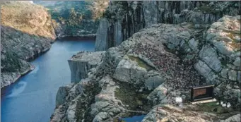  ?? CARINA JOHANSEN / NTB SCANPIX VIA AFP ?? People gather in the mountains near Preikestol­en (The Pullpit Rock) in western Norway, on Wednesday, to see the movie Some of the scenes in the movie were filmed at the Norwegian landmark in November.