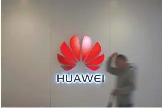  ?? REUTERS ?? A MAN walks by a Huawei logo at a shopping mall in Shanghai, China in this Dec. 6 photo.