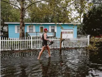  ?? Tom Copeland / Associated Press ?? Jayme Cayton walks up to her flooded home for the first time after Hurricane Florence hit Emerald Isle, N.C. Thousands of people in the Carolinas are waiting to return to their homes.
