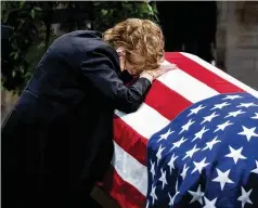  ?? JABIN BOTSFORD/WASHINGTON POST ?? Elizabeth Dole places her head on the casket of her late husband, former Sen. Robert Dole, as he lay in state in the U.S. Capitol on Thursday. He died Sunday at age 98.