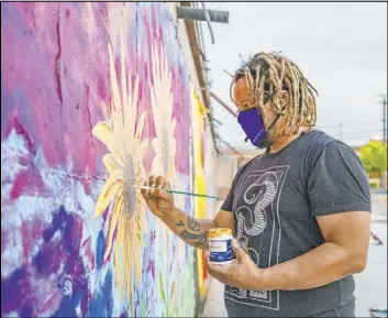 ??  ?? Las Vegas artist Brent Holmes works on a mural Aug. 18. “To me, the Moulin Rouge is a moment. This is where Black folks crossed the color barrier for the first time.”