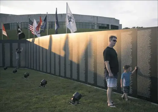  ?? Haley Nelson/Post-Gazette photos ?? James Rowlands of Allison Park and his son, Brody, 4, visit the Traveling Vietnam Memorial Wall after a swim at the Hampton Community Swimming Pool on Thursday at Hampton Community Park.