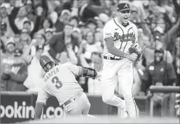 ?? JOHN BAZEMORE AP ?? Braves first baseman Matt Olson celebrates doubling up Phillies’ Bryce Harper at first to end Game 2.