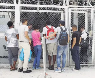  ??  ?? Men wait at the entrance of the registrati­on office at the Moria refugee camp on the island of Lesvos, in a photo published yesterday. Lesvos is also hosting around 4,000 migrants at Moria and an unofficial camp at Kara Tepe.