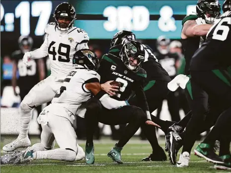  ?? Dustin Satloff / Getty Images ?? The New York Jets’ Zach Wilson is sacked by the Jacksonvil­le Jaguars’ Andre Cisco during the first quarter at MetLife Stadium on Thursday in East Rutherford, N.J.