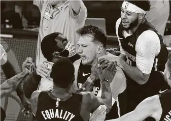  ?? Kevin C. Cox / Getty Images ?? The Mavericks mob Luka Doncic after his game-winning 3-pointer at the end of overtime against the Clippers in Game 4 on Sunday. The win evened the series at 2-2.