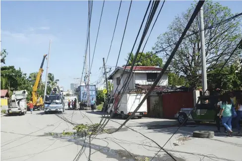  ?? IAN PAUL CORDERO/PN ?? IT WAS ALL A MESS in Barangay Lapuz Norte, Lapuz, Iloilo City on Saturday, June 16 – electrical wires and cables of Panay Electric Company (PECO) and cable and telecommun­ication companies got tangled on a trailer truck that passed by Rizal Street. Five...