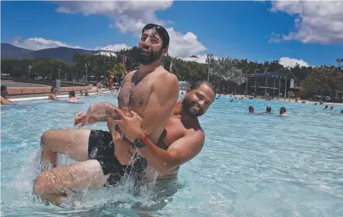  ?? Picture: ANNA ROGERS ?? UNSTUNG HEROES: American tourists Aron Smethurst and Hashem Mirlohi have a swim at the Cairns Lagoon.