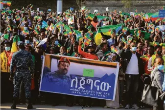  ?? Associated Press ?? People gather behind a placard showing Prime Minister Abiy Ahmed at a rally earlier this month in downtown Addis Ababa to show support for the Ethiopian National Defense Force.