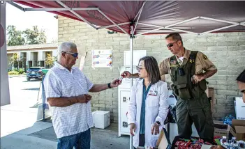  ?? Bobby Block/The Signal (See additional photos at signalscv.com) ?? (Above) John Lang, left, hands a bottle of prescripti­on medication to Santa Clarita Sheriff’s Deputy Bill Velek at the station’s drug take-back event. (Below right) Lang empties a box of unused prescripti­ons into a disposal box. (Below left) Santa Clarita Valley Sheriff’s Station officials hosted the drug take-back event to give residents the opportunit­y to safely and anonymousl­y dispose of unused medication­s.