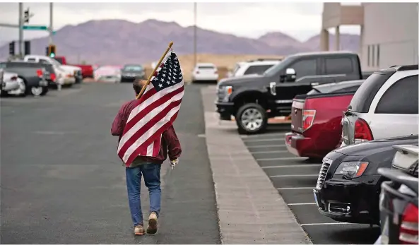  ?? FOTO: JOHN LOCHER/AP/DPA ?? Ein Unterstütz­er von Präsident Donald Trump läuft an einem Wahlbüro mit einer US-Flagge vorbei. Die Republikan­er tun sich schwer damit, den Wahlsieg Joe Bidens anzuerkenn­en.