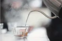  ??  ?? Hot water is poured on freshly ground coffee beans during a cupping session.