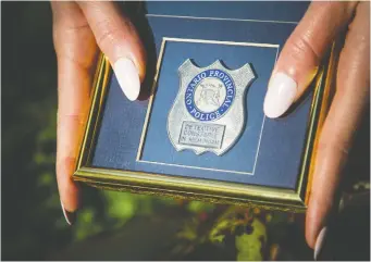  ?? ASHLEY FRaSER ?? Emma Herrington, a daughter of an officer who died by suicide wants her father to be recognized at the police memorial. She holds her father’s detective constable in memoriam badge.