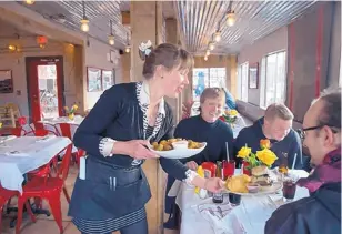  ?? EDDIE MOORE/JOURNAL ?? From left, Serena Konkin serves dinner to Serjoscha Wiemer, Toby Comradi and Tim Glaser at The Hollar restaurant in Madrid, N.M.